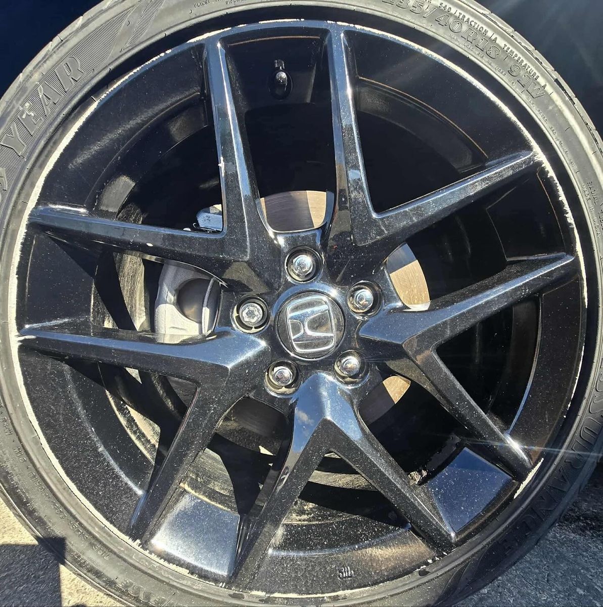 Black alloy Honda wheel with lip rash, before repair