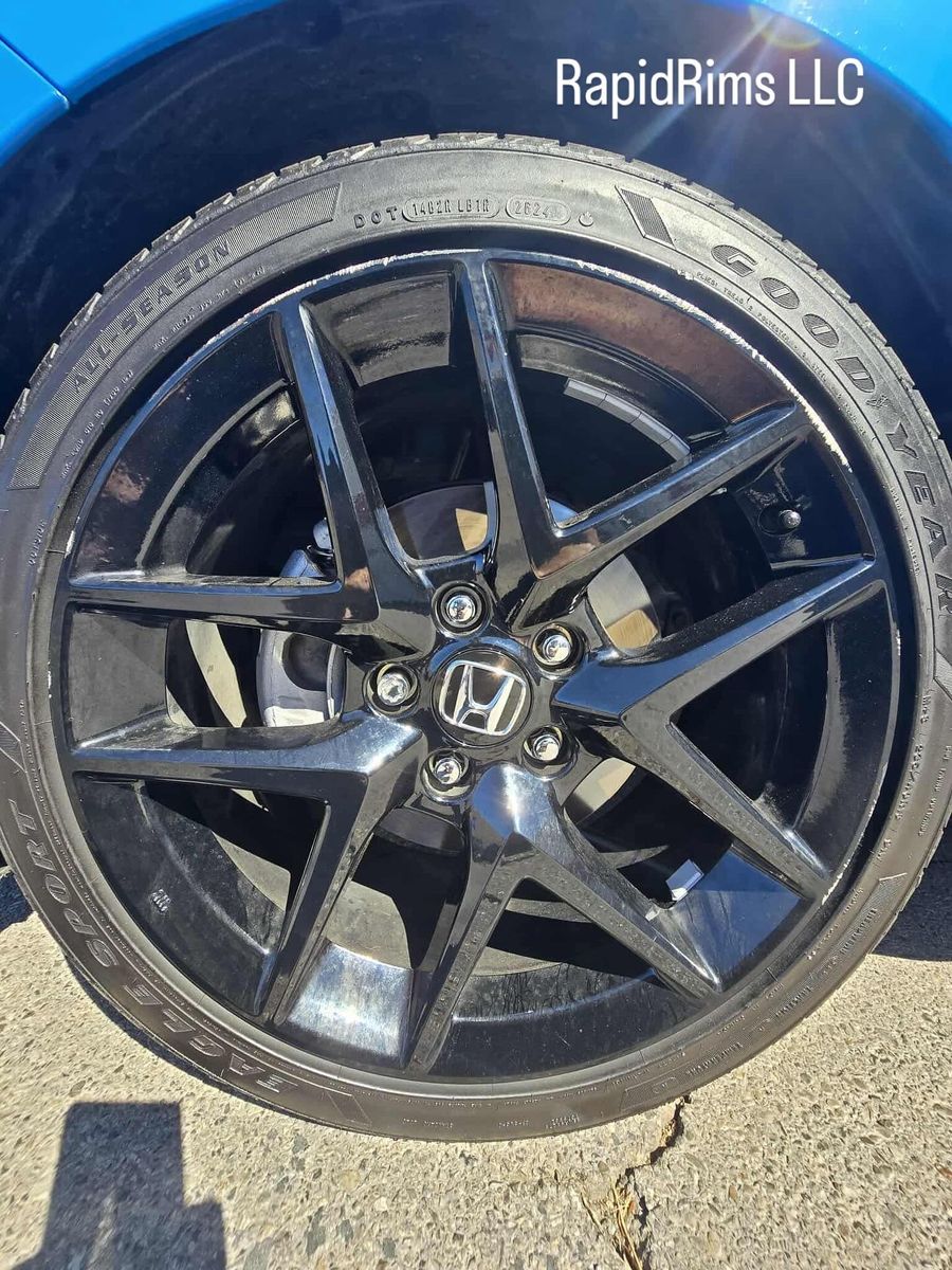 Gloss black Honda wheel with curb rash on the lip, before repair