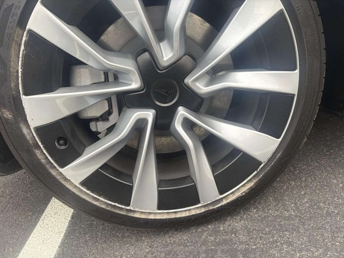 Silver Tesla wheel with curb rash, before repair
